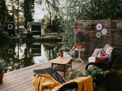 um deque com cadeiras e uma mesa ao lado de um lago em Chalet in Geel in quiet location by the water em Geel