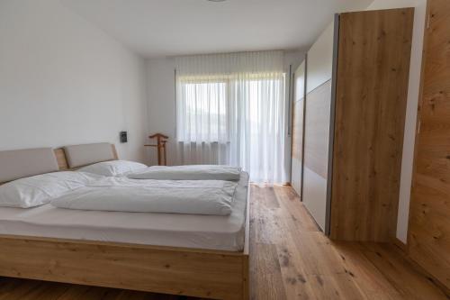 una camera da letto con letto, lenzuola bianche e pavimenti in legno di Innermoarhof a Rifiano
