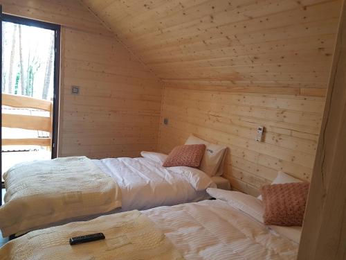 two beds in a room with wooden walls at Domek Shrek in Boszkowo