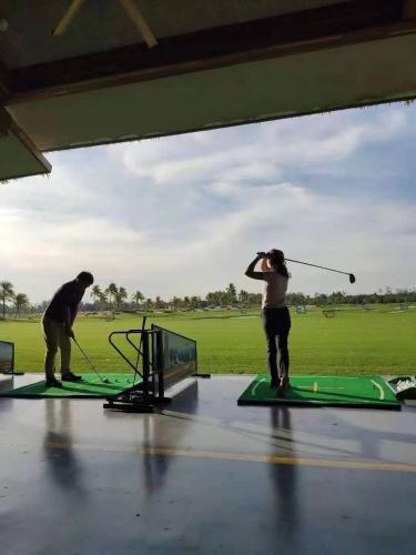 a woman swinging a golf club on a golf course at Forest City Golf Hotel in Nusajaya