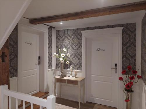 a hallway with two white doors and a table with flowers at AnaCapri Gästehaus Girona in Ueckermünde