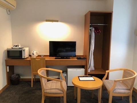 a room with a desk with a computer and chairs at Hotel Plaisir Tachikawa in Tachikawa