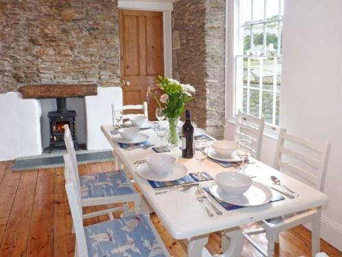 a white table with dishes and a bottle of wine at Rose Cottage in St Austell