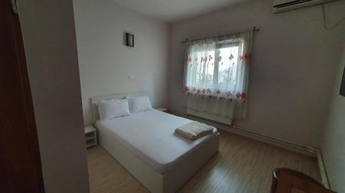 a small bedroom with a white bed and a window at Pensiunea Elmo in Constanţa