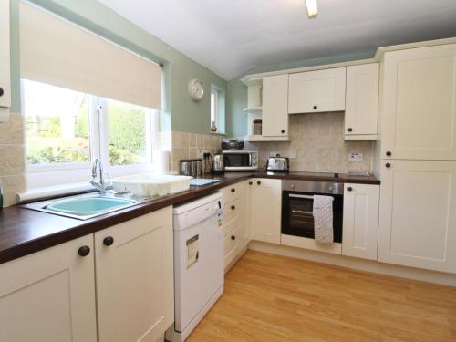 a kitchen with white cabinets and a window at 2 Mellfell View in Penrith