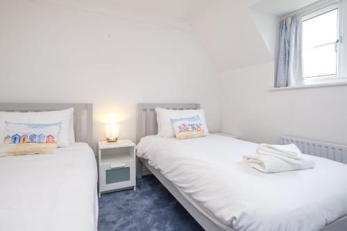 two twin beds in a room with a window at Bryony Cottage in Aldeburgh