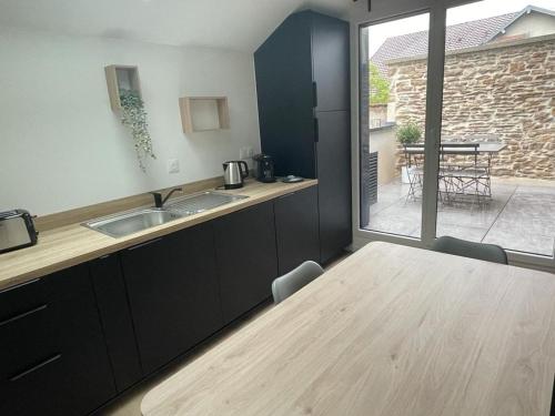 uma cozinha com uma mesa de madeira e uma grande janela em LOUE ET PASSION - DOMAINE LOUE PAISIBLE - Calme - Terrasse - Parking em Chouzelot