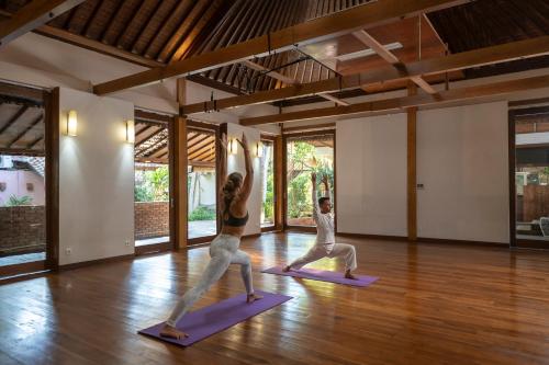 Dos mujeres haciendo una pose de yoga en una habitación en Adiwana Svarga Loka - A Retreat Resort en Ubud