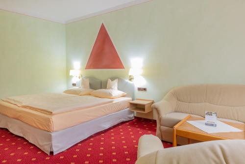 um quarto de hotel com uma cama e um sofá em Goldener Schwan Hotel Garni em Bad Windsheim