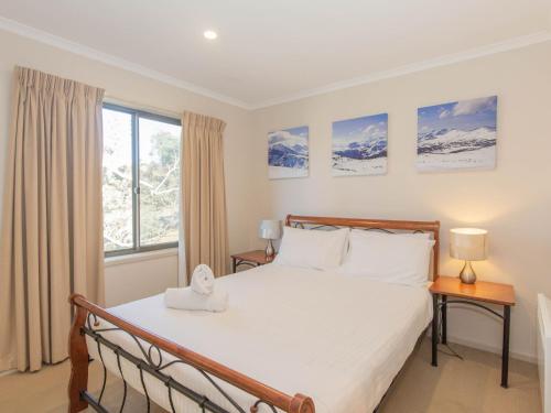 un dormitorio con una cama y una ventana en Boronia 5 30 Nettin Circuit, en Jindabyne