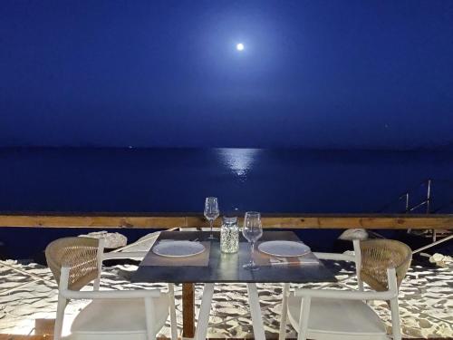 a table with chairs and wine glasses on the beach at NISSEA Boutique Hotel in Kardamaina