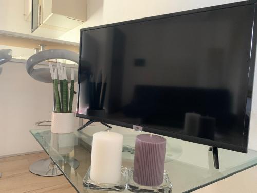 una TV a schermo piatto seduta su un tavolo di vetro con candele di Appartamento confortevole a Cagliari