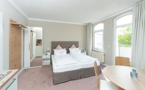 キュールングスボルンにあるAppartementhaus Zum Strandkorbの白いベッドルーム(ベッド1台、テーブル付)