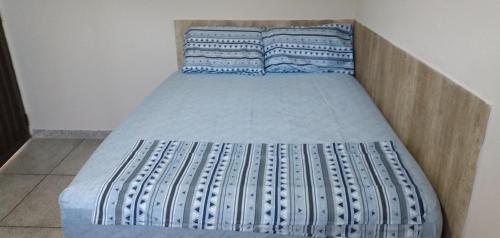uma cama com lençóis e almofadas azuis e brancos em LOCANDA DA SERRA - Aptos Mobiliados e Suítes por Temporada em Barra do Garças