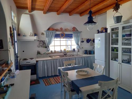 eine Küche mit einem Tisch und Stühlen sowie einem Kühlschrank in der Unterkunft Exclusive Beach House in Gavrio