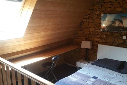 a bedroom with a bed in a stone wall at L'abreuvoir, Gite du 18 siecle, accés indépendant in Carsac-Aillac