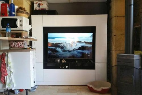 a flat screen tv on a wall in a living room at L'abreuvoir, Gite du 18 siecle, accés indépendant in Carsac-Aillac