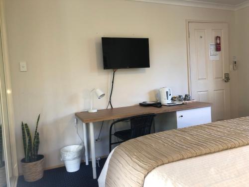 
a hotel room with a television and a bed at Observatory Guesthouse - Adults Only in Busselton
