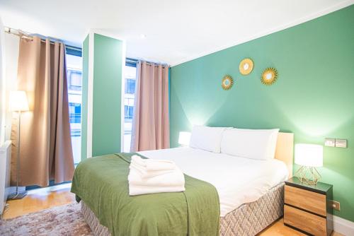 een slaapkamer met een bed met een groene muur bij One Bed Serviced Apt in Farringdon in Londen