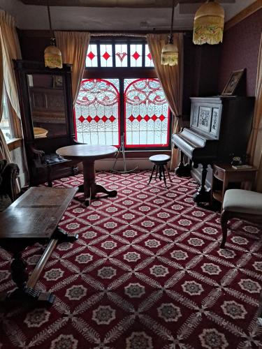 a room with a table and a piano and a window at Van Gilder Hotel in Seward