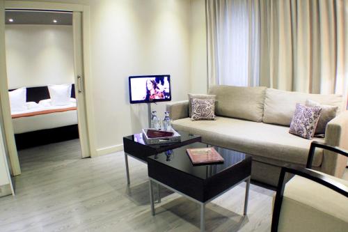 a living room with a couch and a room with a bed at Suites Viena Plaza de España in Madrid