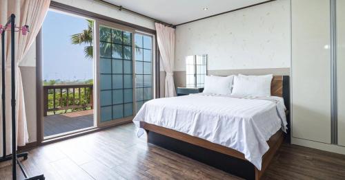 ein Schlafzimmer mit einem großen Bett und einem großen Fenster in der Unterkunft Jeju Time-Travel Pension in Jeju-do