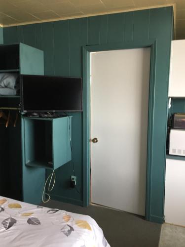 Habitación con cama y puerta con TV en Motel Leblanc, en Carleton-sur-Mer