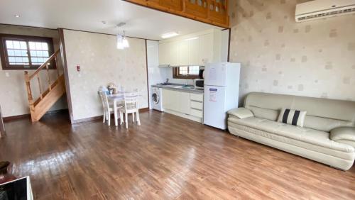 a living room with a couch and a table and a kitchen at Jeju Time-Travel Pension in Jeju