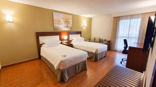 a hotel room with two beds and a television at Dhafra Beach Hotel in Jebel Dhanna