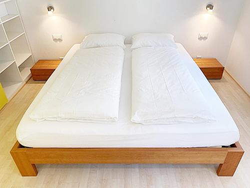 a large bed with white sheets on it in a room at Alpenstil - 60m2 Dachstockwohnung mit Garage - BM186 in Pontresina