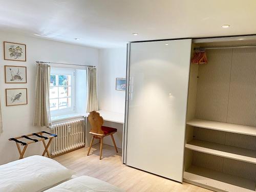 a bedroom with a large glass closet and a chair at Dachwohnung im Alpenstil, 60m2 für 2P, mit Garage - BM186 in Pontresina
