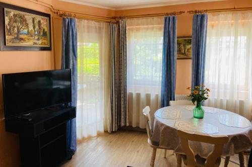 uma sala de estar com uma mesa e uma televisão e uma mesa e cadeiras em Lili nyaralóház em Gyenesdiás