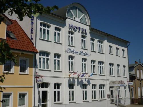 ein großes weißes Gebäude mit Hotelschild drauf in der Unterkunft Hotel Perle am Bodden in Ribnitz-Damgarten
