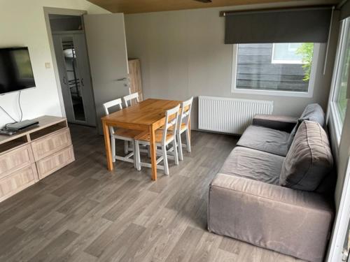 een woonkamer met een bank en een tafel bij Camping Thalassa Belgische Kust Chalet in Bredene