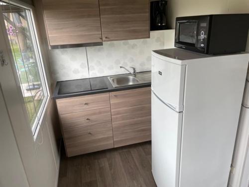 a kitchen with a white refrigerator and a microwave at Camping Thalassa Belgische Kust Chalet in Bredene
