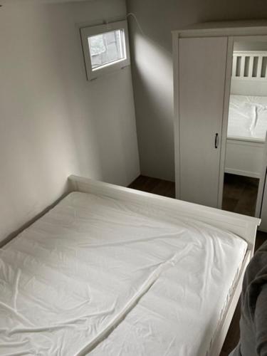Cama blanca en habitación con espejo en Camping Thalassa Belgische Kust Chalet, en Bredene
