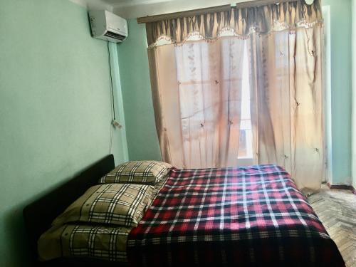 una cama con una manta a cuadros delante de una ventana en Квартира в Новом Афоне с видом на море en Novy Afon