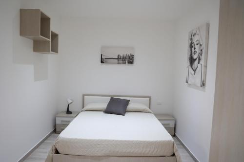 a white bedroom with a white bed with a blue pillow at Casa Vacanze IL GIGANTE in Agrigento