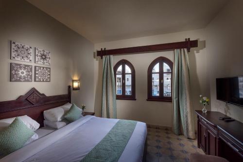 a bedroom with a bed and a tv and windows at Mazar Resort & Spa in Sharm El Sheikh