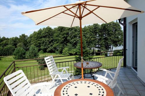 eine Terrasse mit einem Tisch, Stühlen und einem Sonnenschirm in der Unterkunft Villa Mamry in Angerburg