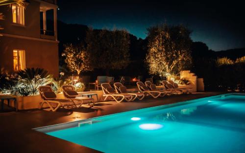 a swimming pool with chairs and a yard at night at Hotel Benaco in Desenzano del Garda