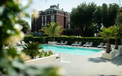 a pool with chairs and a building in the background at Hotel Benaco in Desenzano del Garda