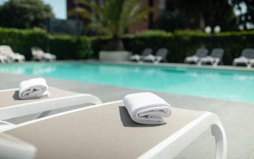 two towels sitting on a chair in front of a swimming pool at Hotel Benaco in Desenzano del Garda