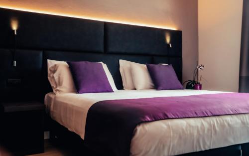 a bedroom with a large bed with purple pillows at Hotel Benaco in Desenzano del Garda