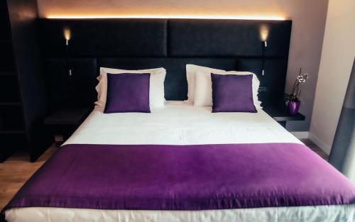 a large bed with purple and white sheets and pillows at Hotel Benaco in Desenzano del Garda