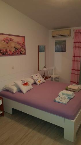 a bedroom with a large bed with purple sheets and pillows at Apartments Boćin Rosso in Hvar