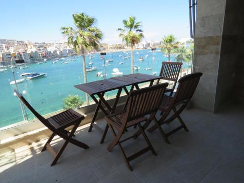 a table and chairs on a balcony with a view of the water at Aquamarine Sea Front Apartments - First Floor in Marsaskala