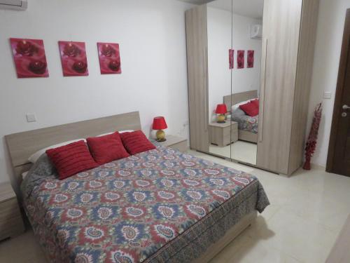 a bedroom with a bed with red pillows and a mirror at Aquamarine Sea Front Apartments - First Floor in Marsaskala