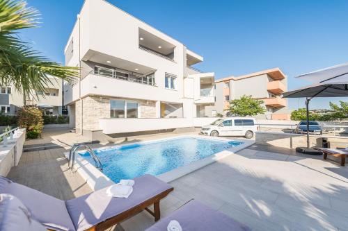 a villa with a swimming pool in front of a building at Apartments & Rooms Danivan Pool Villas in Novalja