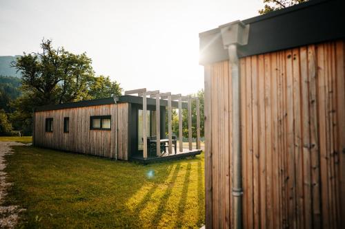 a small cabin in a field next to a building at Chaletpark Petzen in Feistritz ob Bleiburg